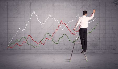 A guy in modern suit standing on a small ladder and drawing a chart on grey wall background with exponential progressing curves, lines