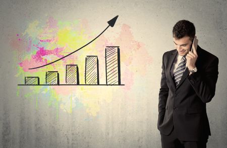 elegant-businessman-standing-front-grey-wall-626401430 An elegant businessman standing in front of a grey wall with colorful growing chart drawing concept