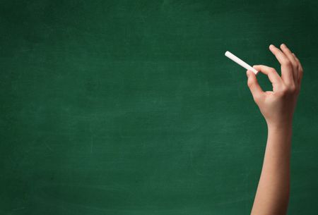 A mature hand writing or drawing on a clean green blackboard with a white chalk.