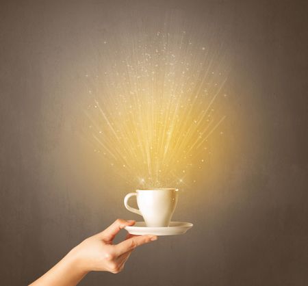 Young female hand holding coffee cup with a beam of light rising out of it 
