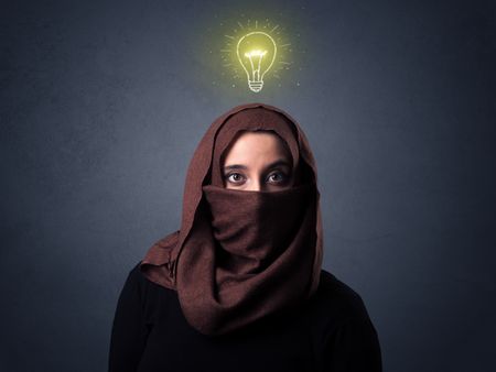 Young muslim woman wearing niqab with lit lightbulb above her head