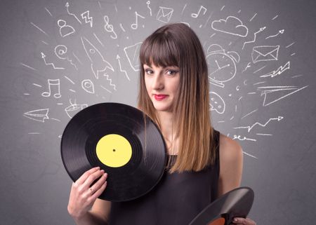 Young lady holding vinyl record on a grey background with mixed scribbles behind her