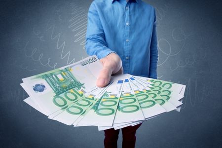 Young businessman holding large amount of bills with grungy background