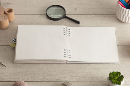 Empty notebook on wood floor with office tools nearby