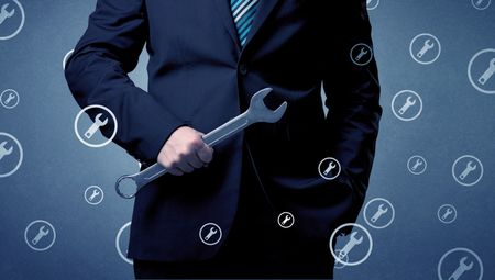 Young serious businesman holding tool with wrench icons around