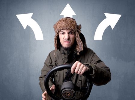 Young man holding black steering wheel with three arrows above his head pointing in different directions