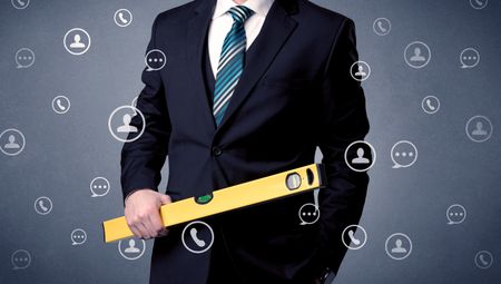 Thoughtful businesman holding tool with communication symbols around