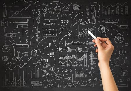 Female hand holding white chalk in front of a blackboard with a business plan drawn on it 