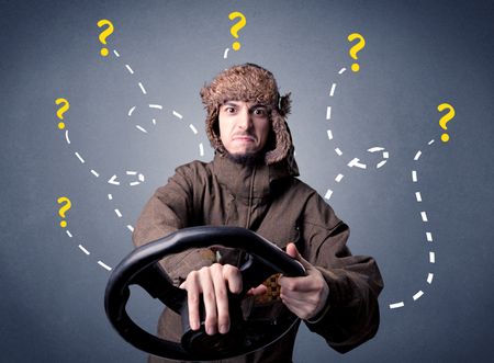 Young man holding black steering wheel with question marks around him