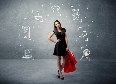 A beautiful young girl in black standing with red shopping bags in front of urban wall background and laptop, shoes, tennis icons concept