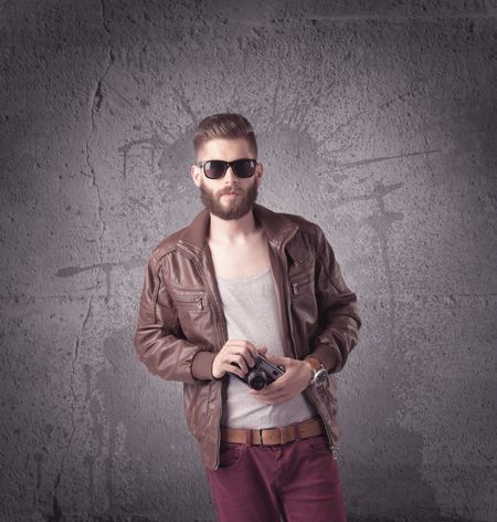 hipster-fashion-model-guy-casual-clothing-628042826 A hipster fashion model guy in casual clothing stnading with mobile phone in front of concrete urban wall background concept
