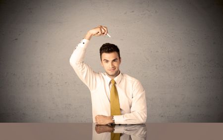 A happy businessman sitting at desk in front of clear grey empty background and drawing around himself with a white chalk concept