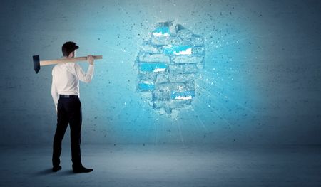 Business man hitting grungy brick wall with huge hammer