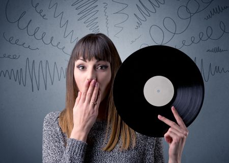 Young lady holding vinyl record on a grey background with scribbles around her