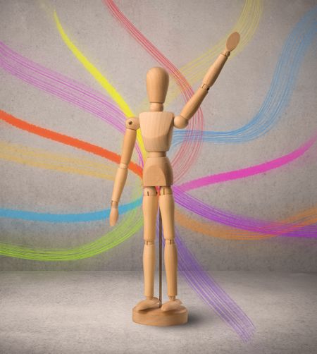 Wooden mannequin posed in front of a greyish background with colorful lines behind it