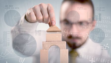 Young handsome businessman using wooden building blocks with data and numbers around him