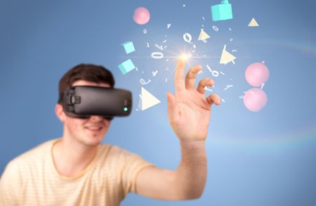 Young impressed man wearing virtual reality goggles with geometric shapes around his hand