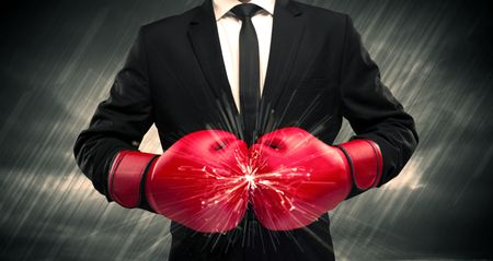 An elegant businessman dressed in suit clashing the boxing gloves on his hand with sparkle concept.