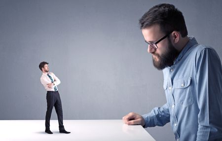 Young professional businessman being angry with an other miniature businessman