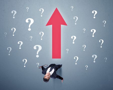 Young contemplating businessman stands in front of a big red arrow and white question marks