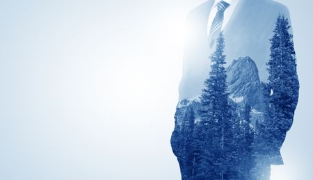 Young businessman standing and meditate with trees on the background 