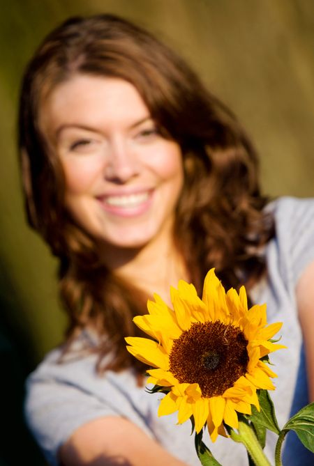 happy girl smiling and offering a sunflower