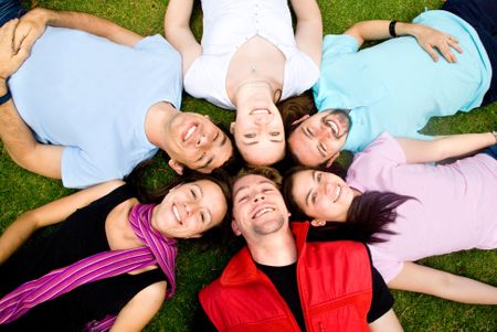 friends having fun portrait in a park lying on the grass with heads together