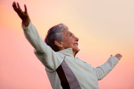 Happy elder woman with arms outstretched and smiling