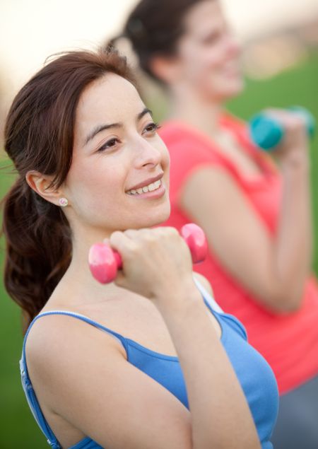 Beautiful girls exercising outdoors with free weights
