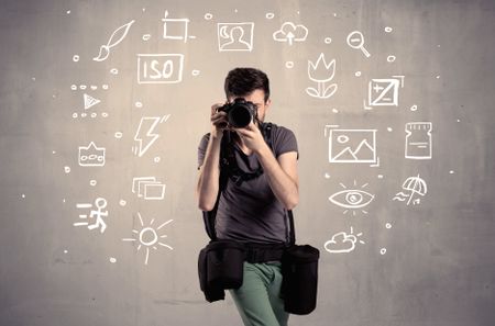 An amateur hobby photographer learning to use a professional digital camera with camera settings icons on the background wall concept