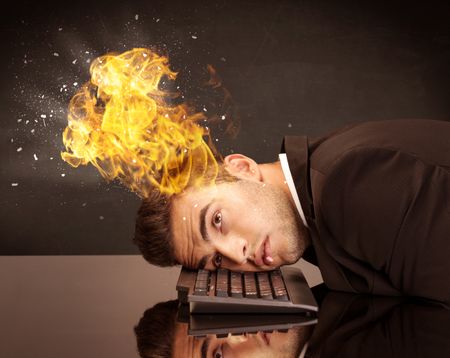 A depressed businessman banging his head in a keyboard and shouting with his head on fire, reflecting on desk