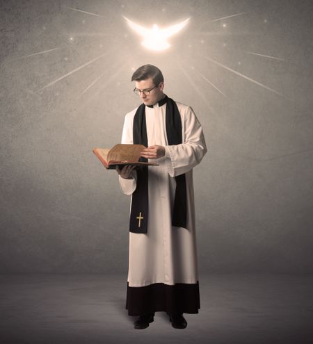 A holy priest reading a prayer from the holy bible with illustrated glowing angel above his head concept.