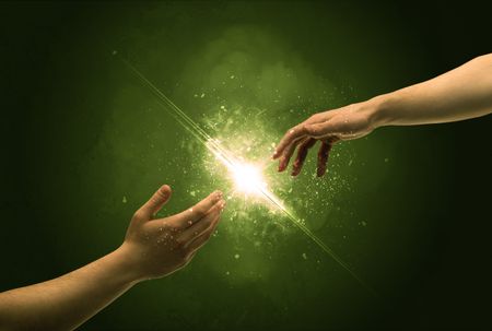 Two naked male hands about to touch, lighting the spark with modest explosion in front of green background concept
