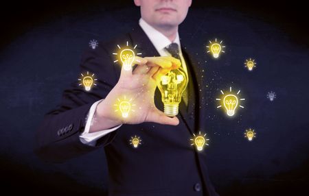 A creative businessman has a bright idea concept with office worker holding light bulb in foreground.