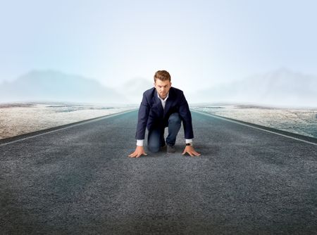 Young determined businessman kneeling before blank running track 