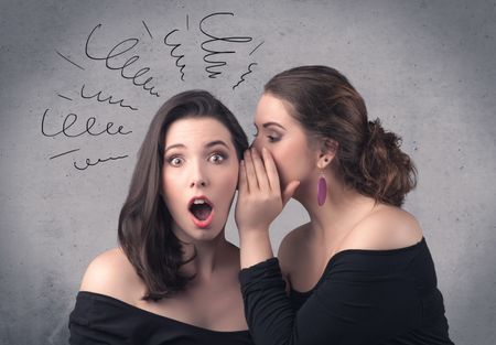 A cute teen caucasian girl telling secret things to her girlfriend dressed in black dress concept with drawn lines, curves, spirals on grey wall background.