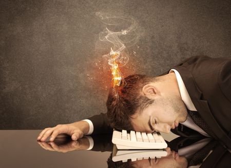 A frustrated businessman resting his head on a keyboard and shouting with his hair on smoke, catching fire