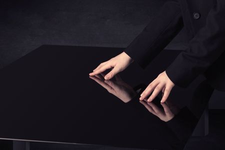 Close up of a hand touching smart table with copy space on black background
