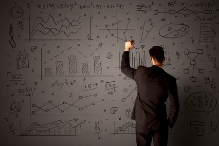 Young businessman in black suit standing in front of detailed calculations 
