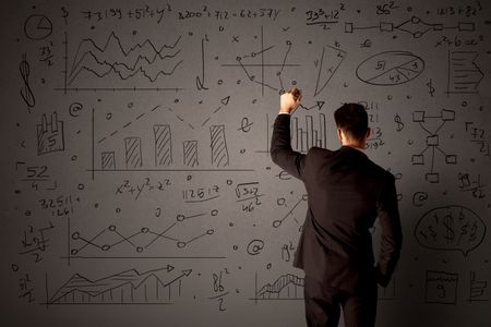 Young businessman in black suit standing in front of detailed calculations