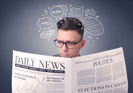 Puzzled young businessman reading daily newspaper with speech bubbles above his head