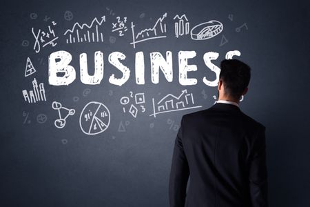 Young businessman in black suit standing in front of a detailed business plan 