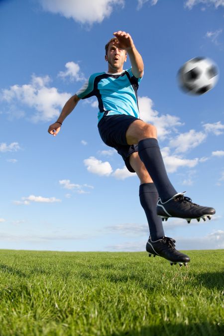 Handsome male football player kicking the ball