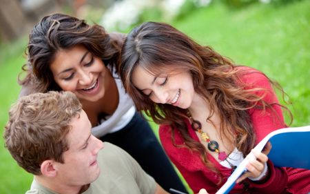 Happy group of students with a notebook smiling outdoors
