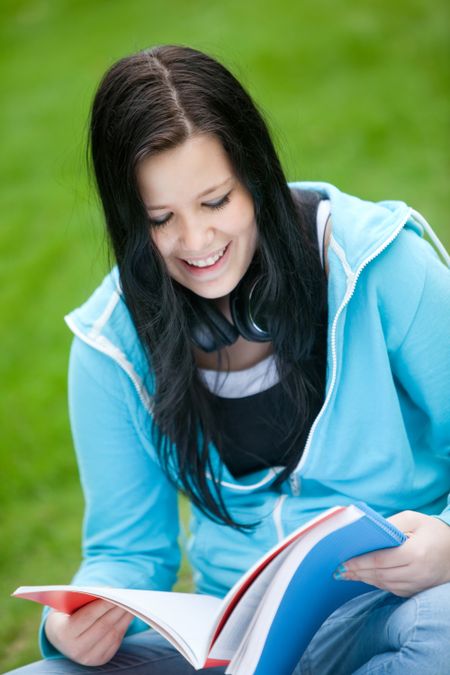 Female student outdoors holding a notebook and smiling