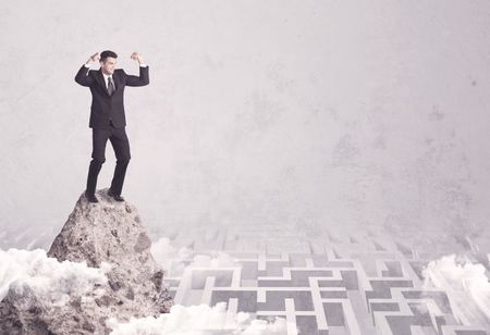 Maze is no challenge for successful businessman standing on top of a cliff as he is the best at solving problems concept