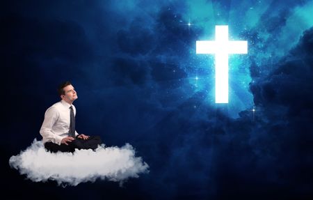 Caucasian businessman sitting on a white fluffy cloud looking and wondering at a big bright glowing cross