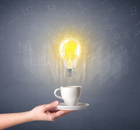 Young female hand holding coffee cup with a lightbulb and alphabet letters above it