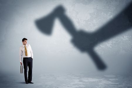 Businessman afraid of a huge shadow hand holding an axe concept on background