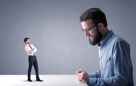 Young professional businessman being angry with an other miniature businessman